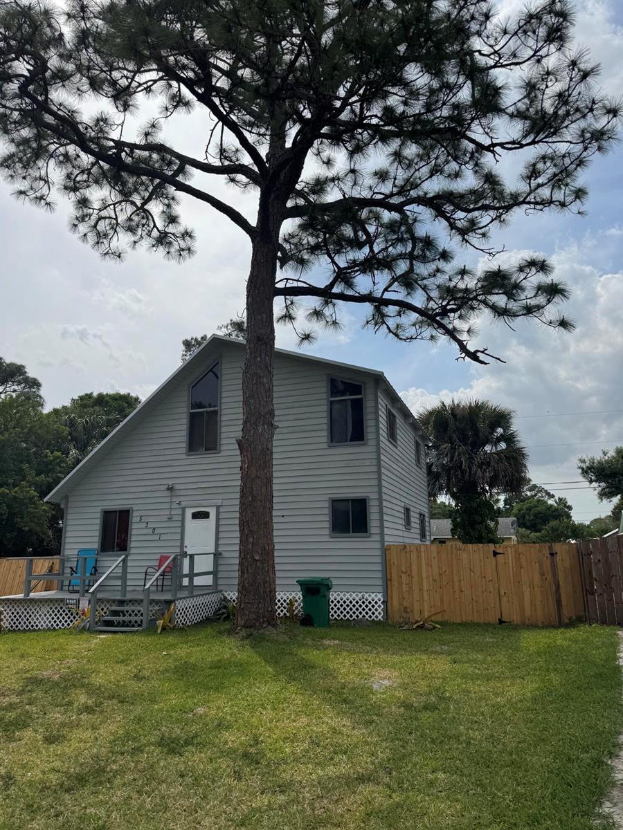 A two-story gray house with a large pine tree in the front yard — 5301 Sunset Boulevard, Fort Pierce FL 34982, FORT PIERCE, FL