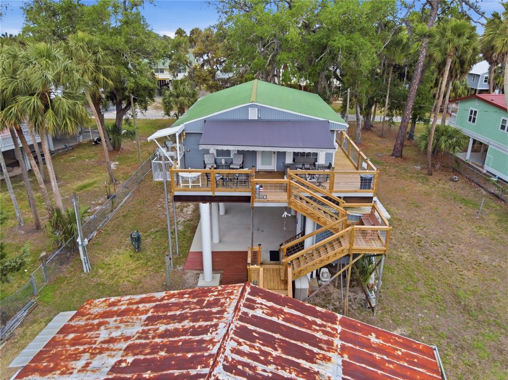 An elevated house with a green roof, large wooden deck, and stairs leading to ground level — 547 SE 205TH STREET, SUWANNEE, FL