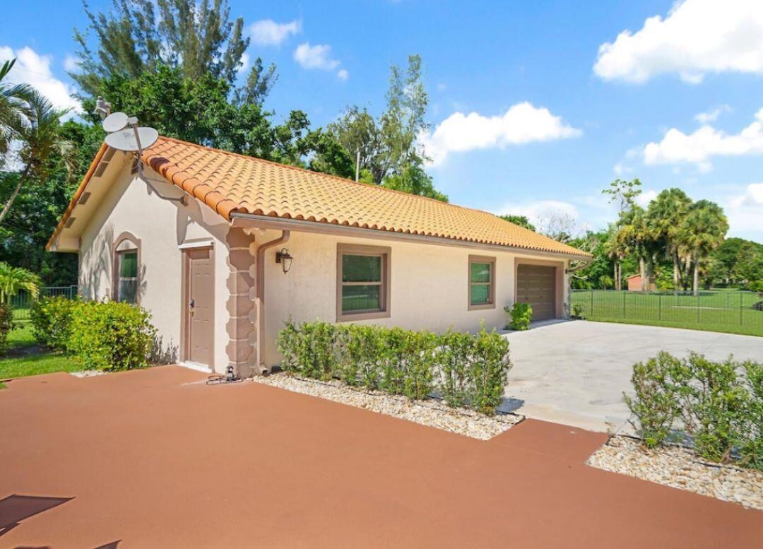 A single-story house with a terracotta tile roof, stucco walls, and an attached garage — 14870 Horseshoe Trace, Wellington FL 33414, WELLINGTON, FL