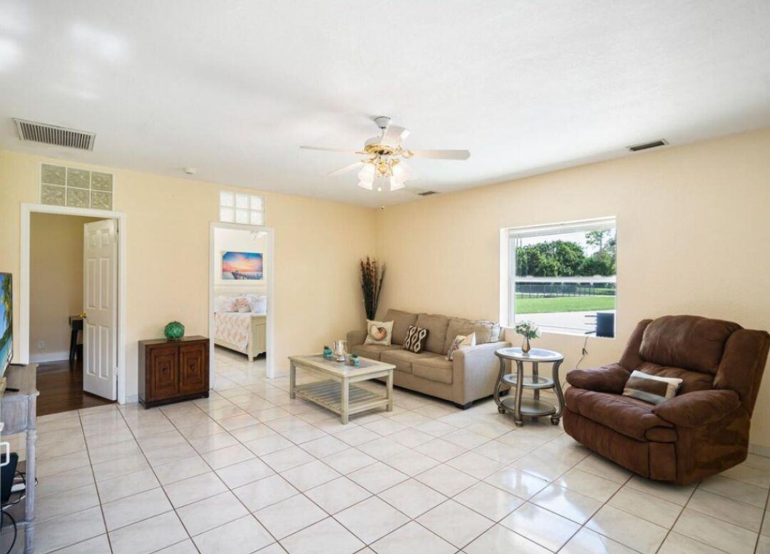 A living room with beige walls, tile flooring, a sofa, a recliner, and a ceiling fan — 14870 Horseshoe Trace, Wellington FL 33414, WELLINGTON, FL