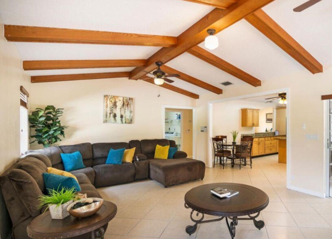 A living room features exposed wooden ceiling beams, a brown sectional sofa, and tile flooring — 14870 Horseshoe Trace, Wellington FL 33414, WELLINGTON, FL