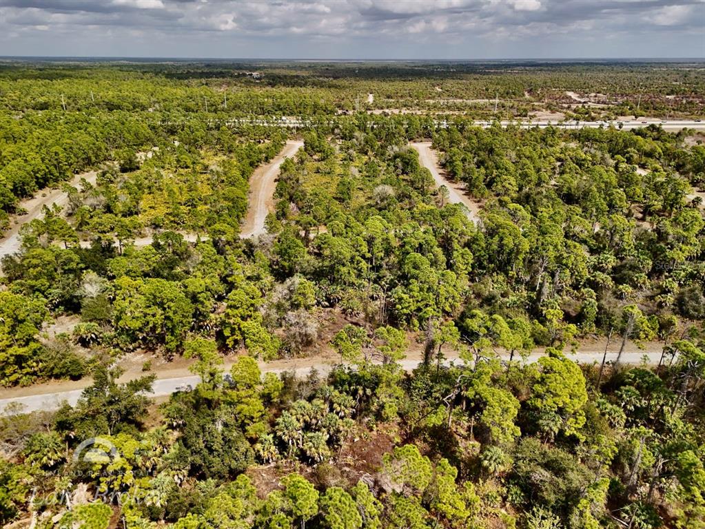 An aerial view shows a wooded lot with dirt roads and a highway in the distance — IRONSIDE STREET, NORTH PORT, FL