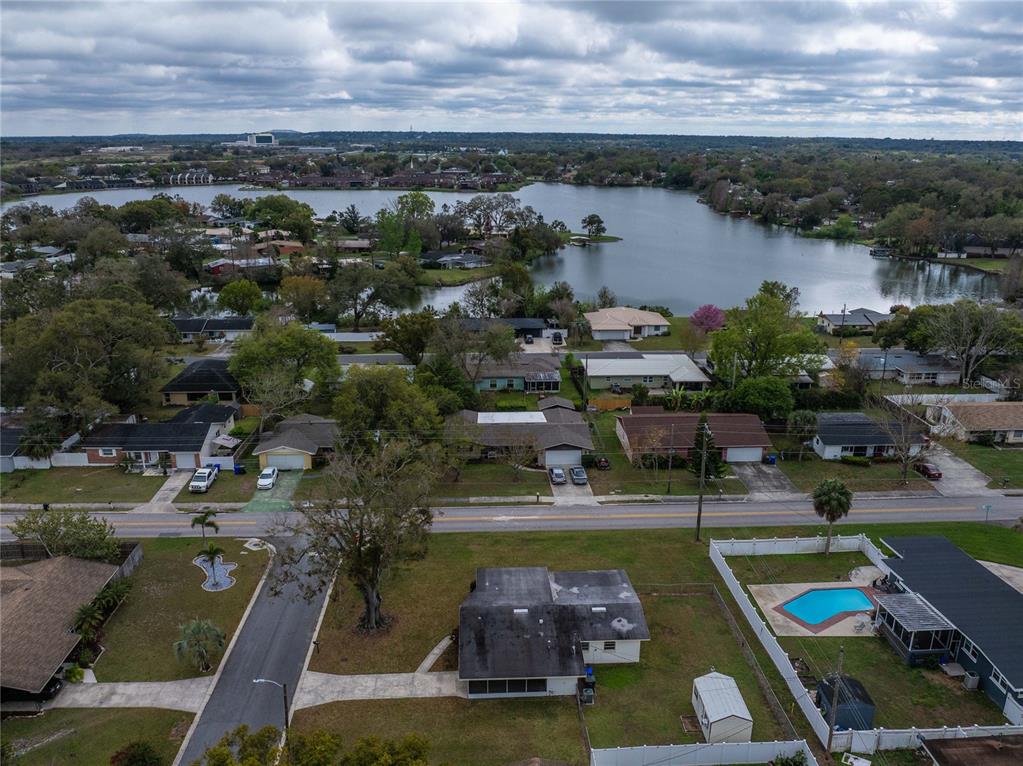 An aerial view shows a residential neighborhood with houses, a street, and a large lake — 1831 STAUNTON AVENUE, LAKELAND, FL