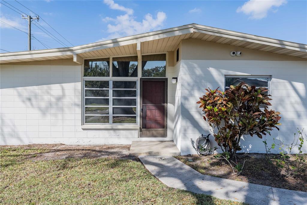 A single-story house with a white block exterior, a front door, and a large window — 1831 STAUNTON AVENUE, LAKELAND, FL
