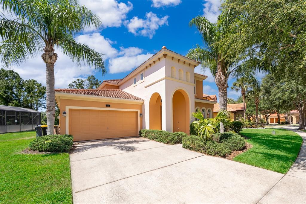 A two-story stucco house with a tile roof, arched entryway, and an attached two-car garage — 171 ORANGE COSMOS BOULEVARD, DAVENPORT, FL