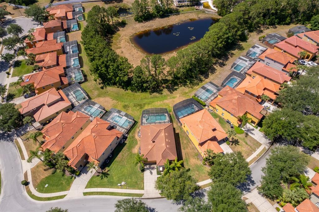 An aerial view shows a suburban neighborhood with houses featuring orange roofs and swimming pools — 171 ORANGE COSMOS BOULEVARD, DAVENPORT, FL