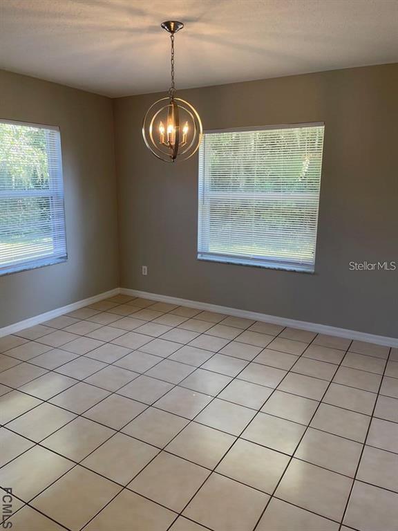 A dining room features beige tile flooring, light gray walls, and a spherical chandelier — 61 FRANCISCAN LANE, PALM COAST, FL