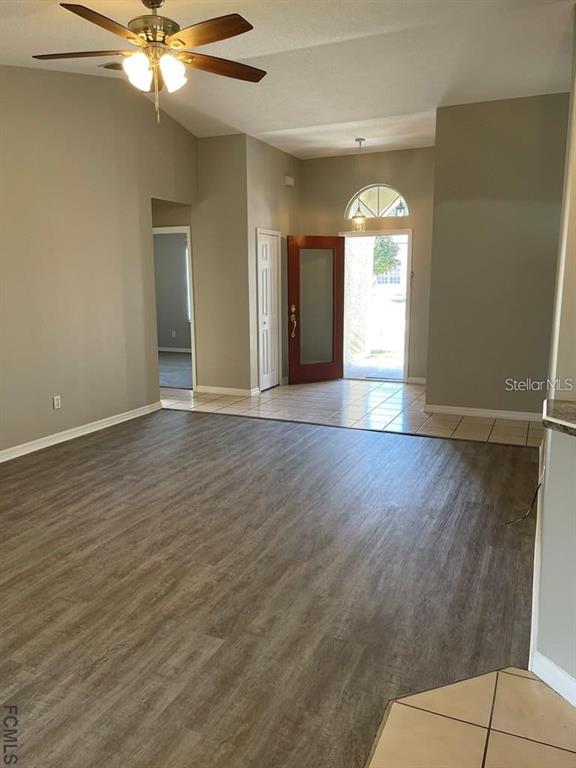 An open living area features wood-look flooring, a ceiling fan, and an entryway with tile — 61 FRANCISCAN LANE, PALM COAST, FL