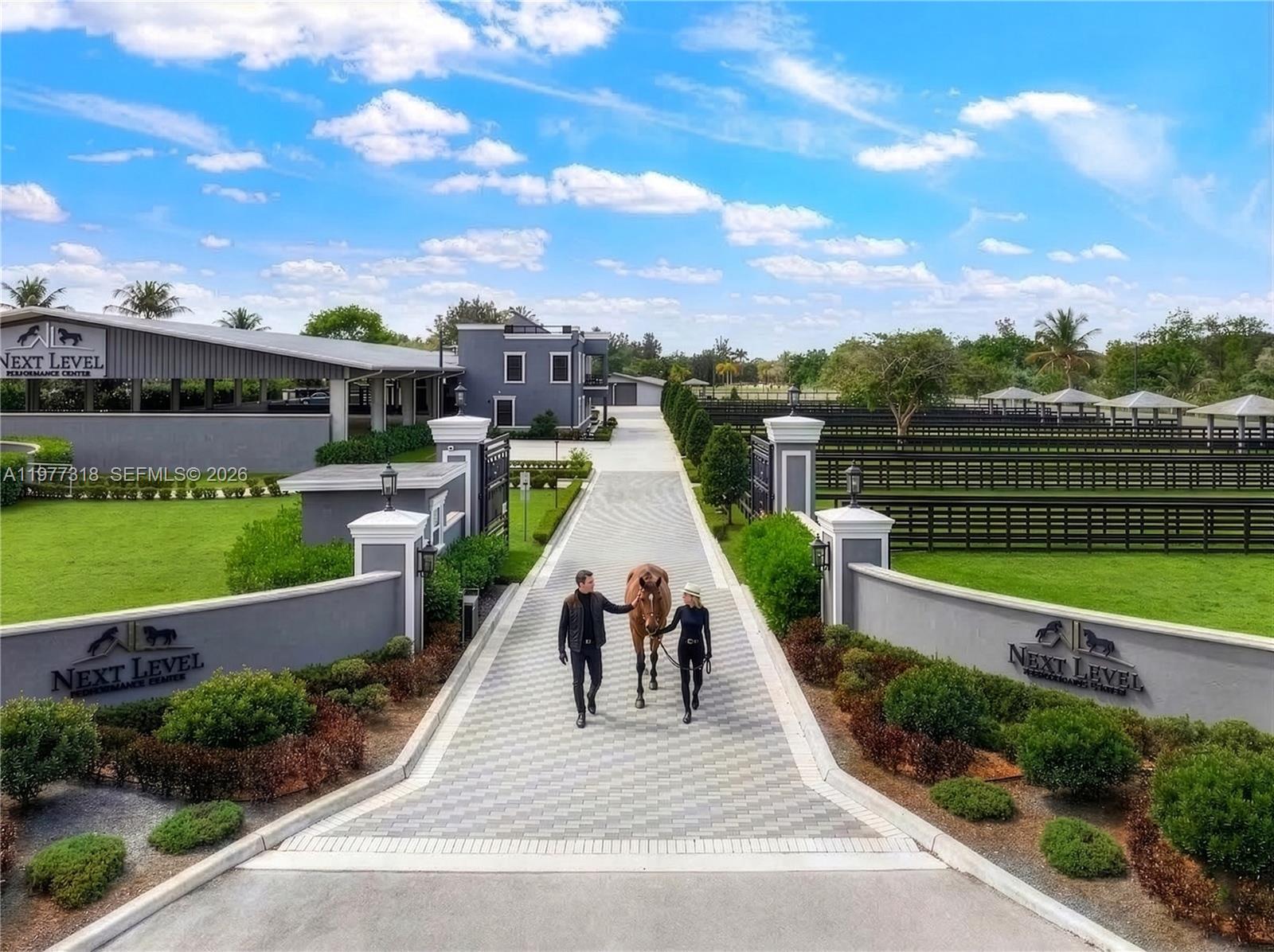 An aerial view shows a couple walking a horse down a paved driveway at an equestrian facility — 2625 SW 148th Ave, Davie FL 33331, DAVIE, FL