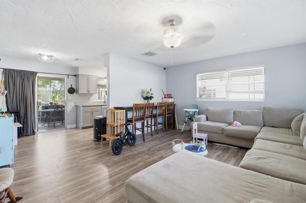 A living room with light wood flooring, a sectional sofa, and a breakfast bar area — 56 S COLUMBUS STREET, BEVERLY HILLS, FL