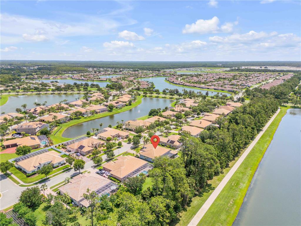 An aerial view shows a residential neighborhood with houses, swimming pools, and several lakes — 3550 GRANDE TUSCANY WAY, NEW SMYRNA BEACH, FL