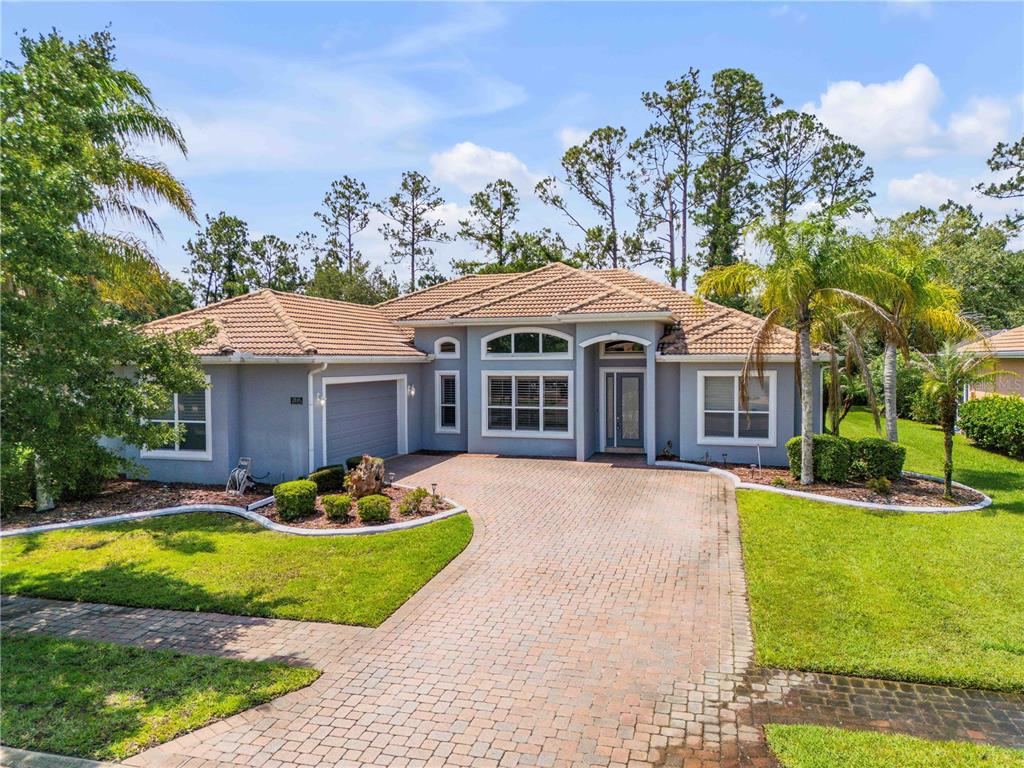A single-story house with a gray stucco exterior, tile roof, and a brick paver driveway — 3550 GRANDE TUSCANY WAY, NEW SMYRNA BEACH, FL