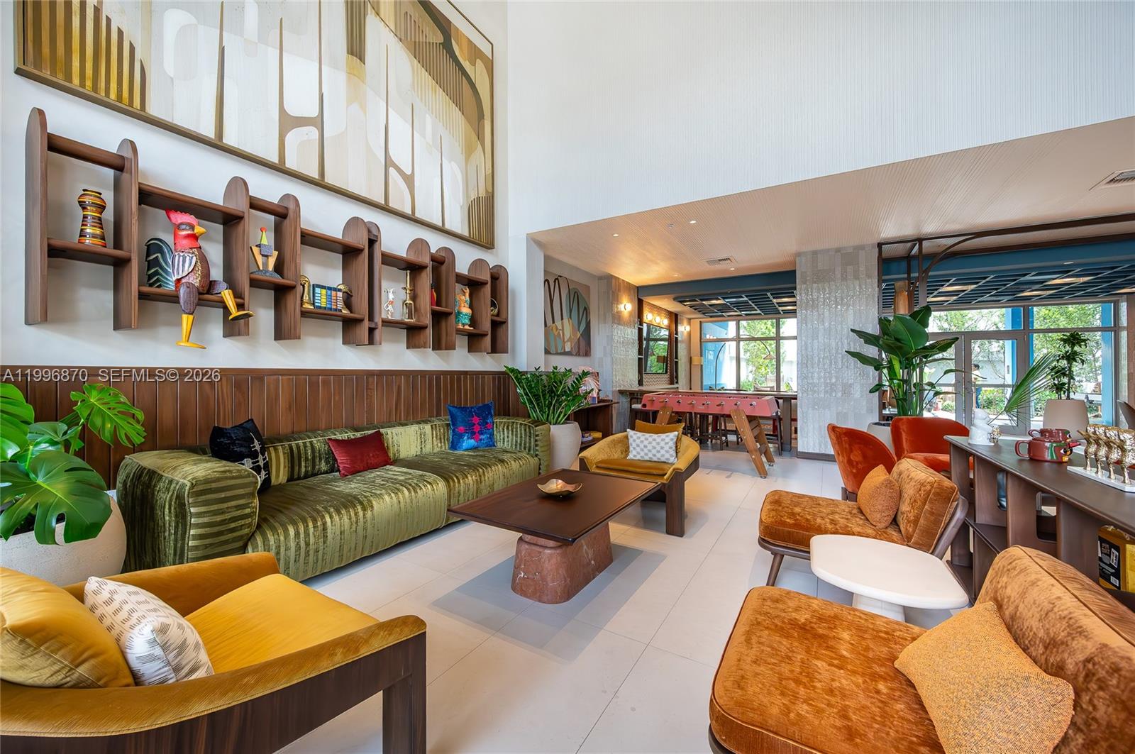 A modern lounge area features a long green velvet sofa, mid-century furniture, and decorative shelving — 1611 SW 2nd Ave # 216, Miami FL 33129, MIAMI, FL