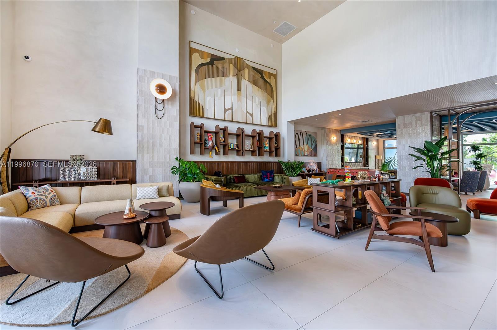 A spacious, high-ceilinged lounge features mid-century modern furniture, large abstract wall art, and tiled flooring — 1611 SW 2nd Ave # 216, Miami FL 33129, MIAMI, FL