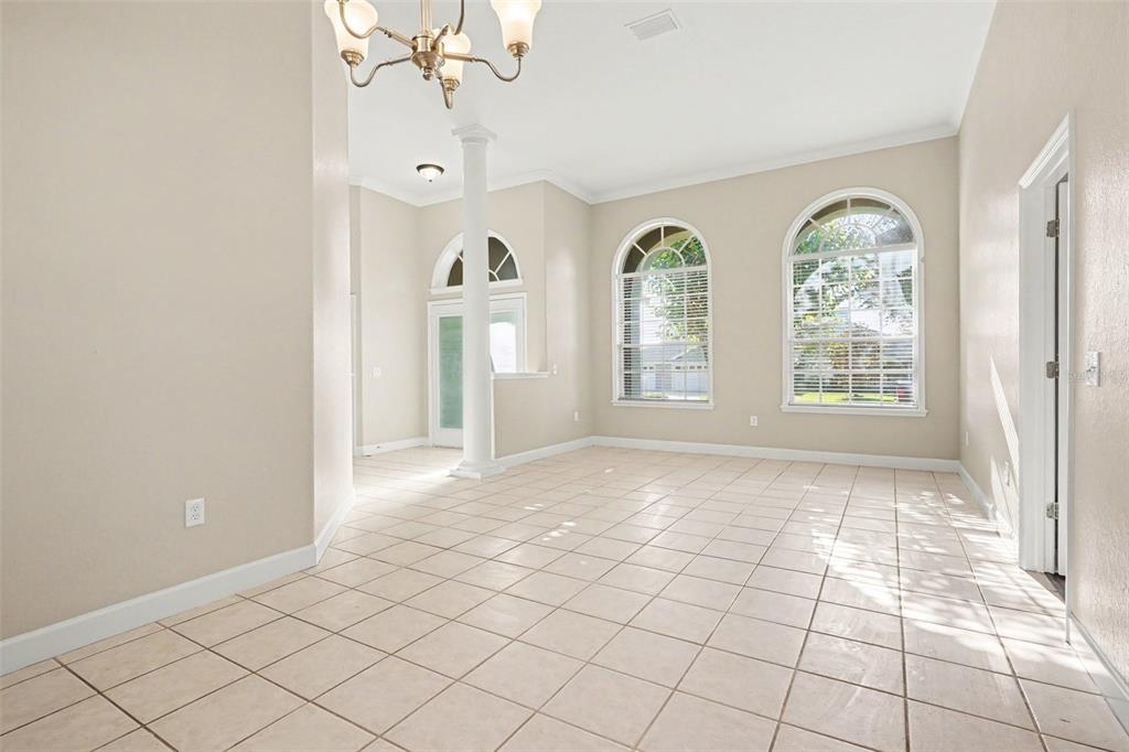 An empty room with beige tile flooring, a white column, and three arched windows — 5535 SUMMERLAND HILLS DRIVE, LAKELAND, FL