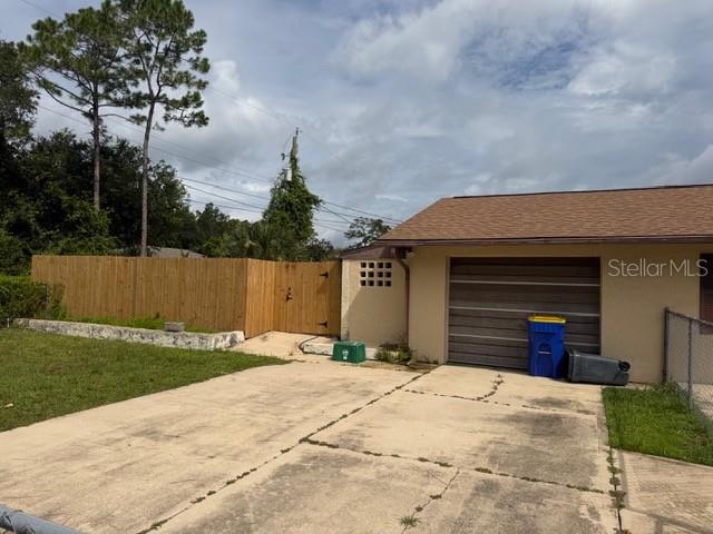 A concrete driveway leads to a garage next to a wooden privacy fence — 3048 UNITY TREE DRIVE, EDGEWATER, FL