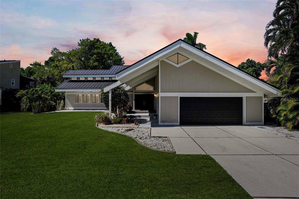 A single-story house with a dark metal roof, beige siding, and a two-car garage — 330 PRATHER DRIVE, FORT MYERS, FL