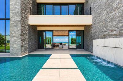 A modern house exterior features a stone facade, a swimming pool, and a stone walkway — VERO BEACH, FL