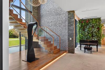 A modern entryway features a floating wooden staircase, a living plant wall, and a piano — VERO BEACH, FL