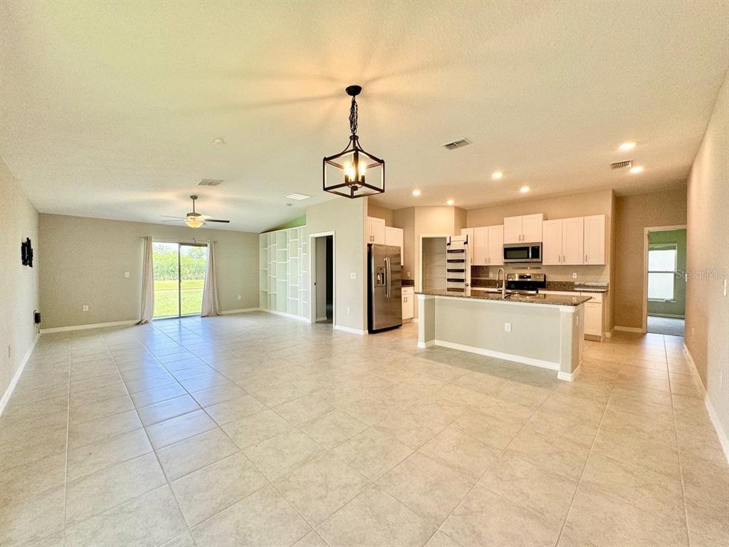 An open-concept kitchen and living area with tile floors, white cabinets, and a kitchen island — 7025 KING CREEK DRIVE, SUN CITY CENTER, FL