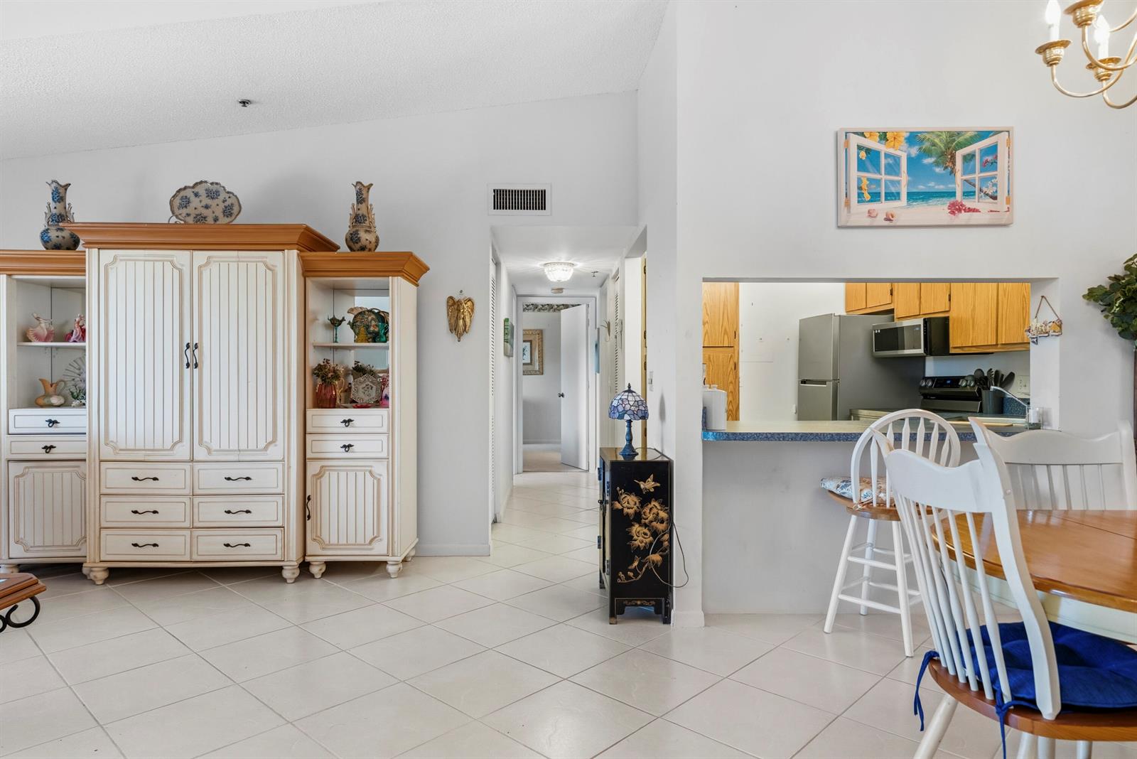 A living room and dining area with tile floors, a large cabinet, and kitchen pass-through — 4452 NE Ocean Blvd # C3, Jensen Beach FL 34957, JENSEN BEACH, FL