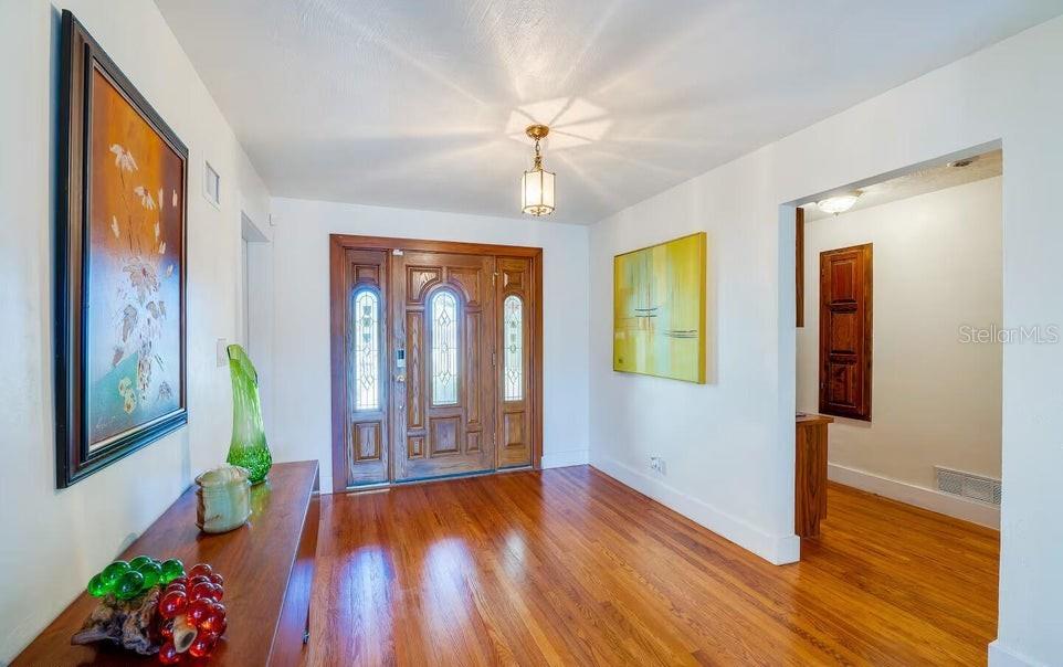 An entryway with hardwood floors, a wooden front door, and artwork on white walls — 1286 JOHN ANDERSON DRIVE, ORMOND BEACH, FL