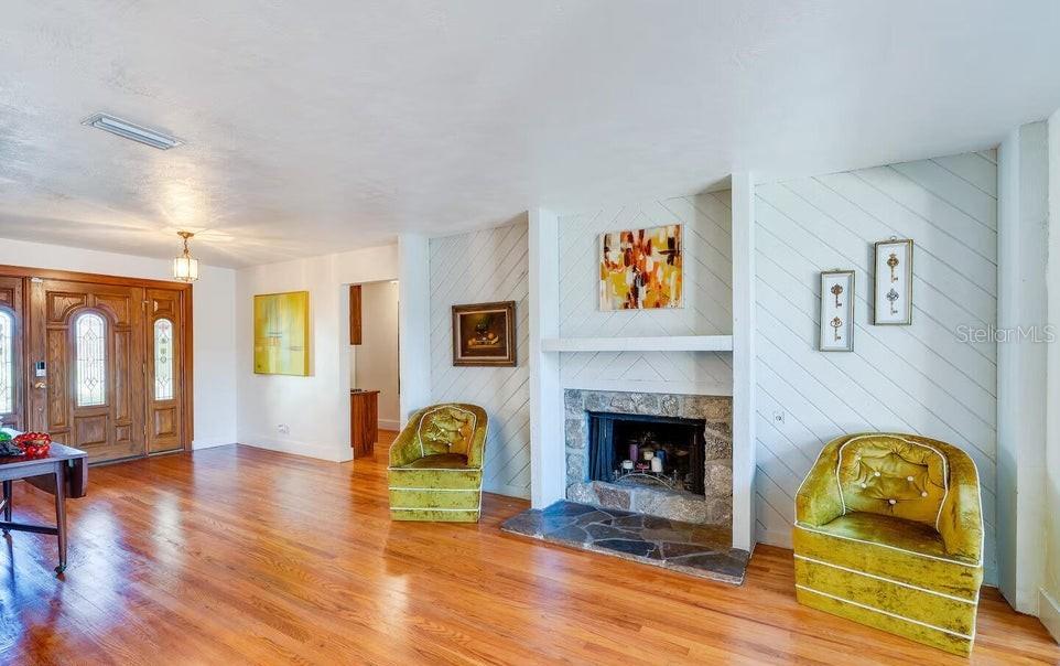 A living room features hardwood floors, a stone fireplace, and two yellow velvet armchairs — 1286 JOHN ANDERSON DRIVE, ORMOND BEACH, FL