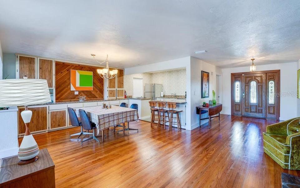 A dining area with wood paneling and a kitchen with bar seating on hardwood floors — 1286 JOHN ANDERSON DRIVE, ORMOND BEACH, FL