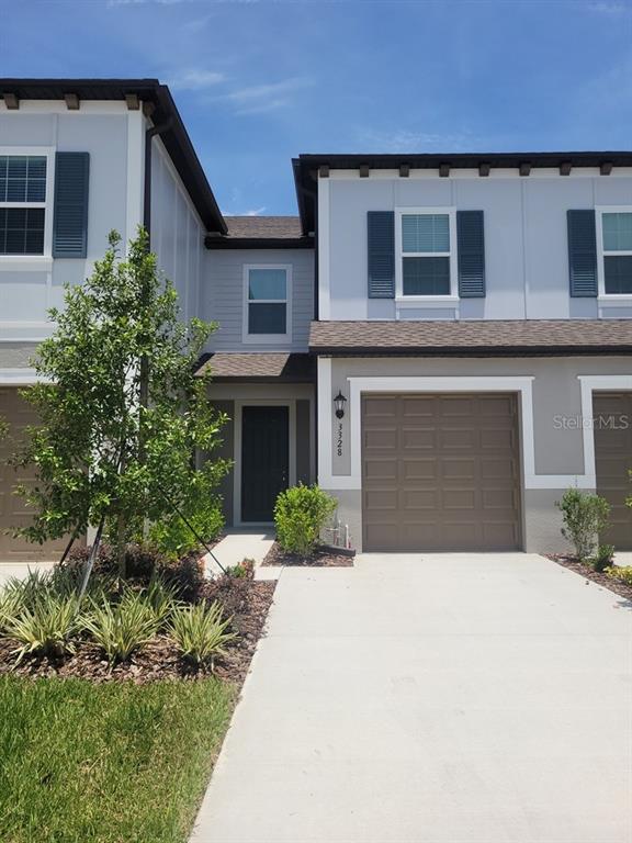 A two-story townhouse exterior features a concrete driveway, a single-car garage, and a front entrance — 3328 LAPIS LAKE DRIVE, ZEPHYRHILLS, FL