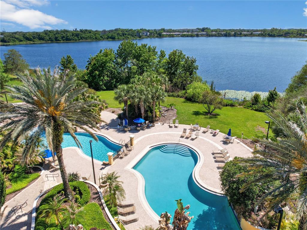 An aerial view shows a swimming pool with lounge chairs overlooking a large lake — 1100 LAKE SHADOW CIRCLE UNIT 2307, MAITLAND, FL
