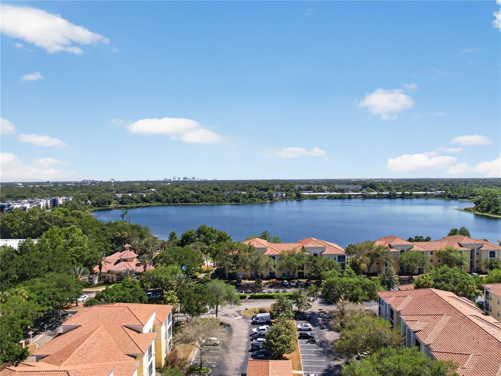 An elevated view of a lake surrounded by apartment buildings with terracotta roofs and trees — 1100 LAKE SHADOW CIRCLE UNIT 2307, MAITLAND, FL