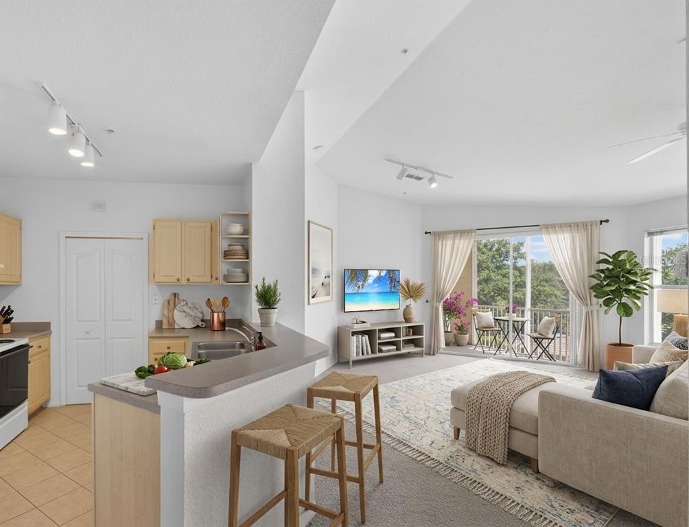 An open-concept kitchen with a breakfast bar overlooks a living room with a balcony — 1100 LAKE SHADOW CIRCLE UNIT 2307, MAITLAND, FL