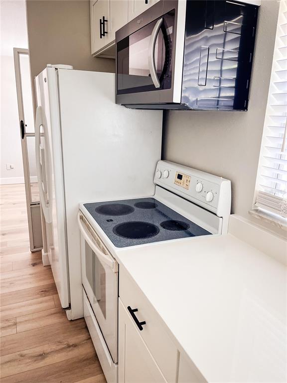 A kitchen features a white refrigerator, a glass-top electric stove, and a mounted microwave — 24862 US HIGHWAY 19 N UNIT 1602, CLEARWATER, FL