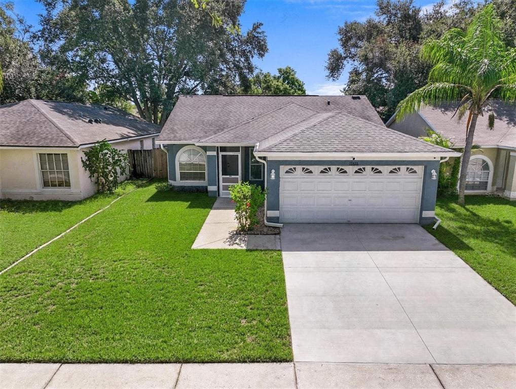 A blue single-story house with a two-car garage, a concrete driveway, and a front lawn — 13616 LARAWAY DRIVE, RIVERVIEW, FL