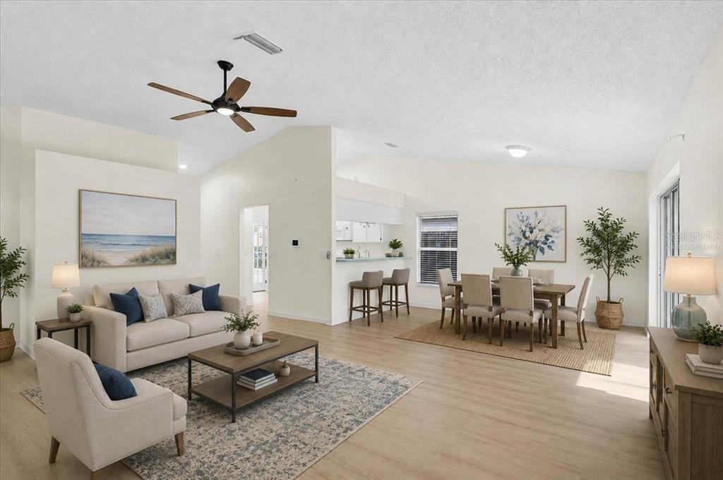 This open-concept living and dining area features vaulted ceilings, light wood flooring, and neutral decor — 13616 LARAWAY DRIVE, RIVERVIEW, FL