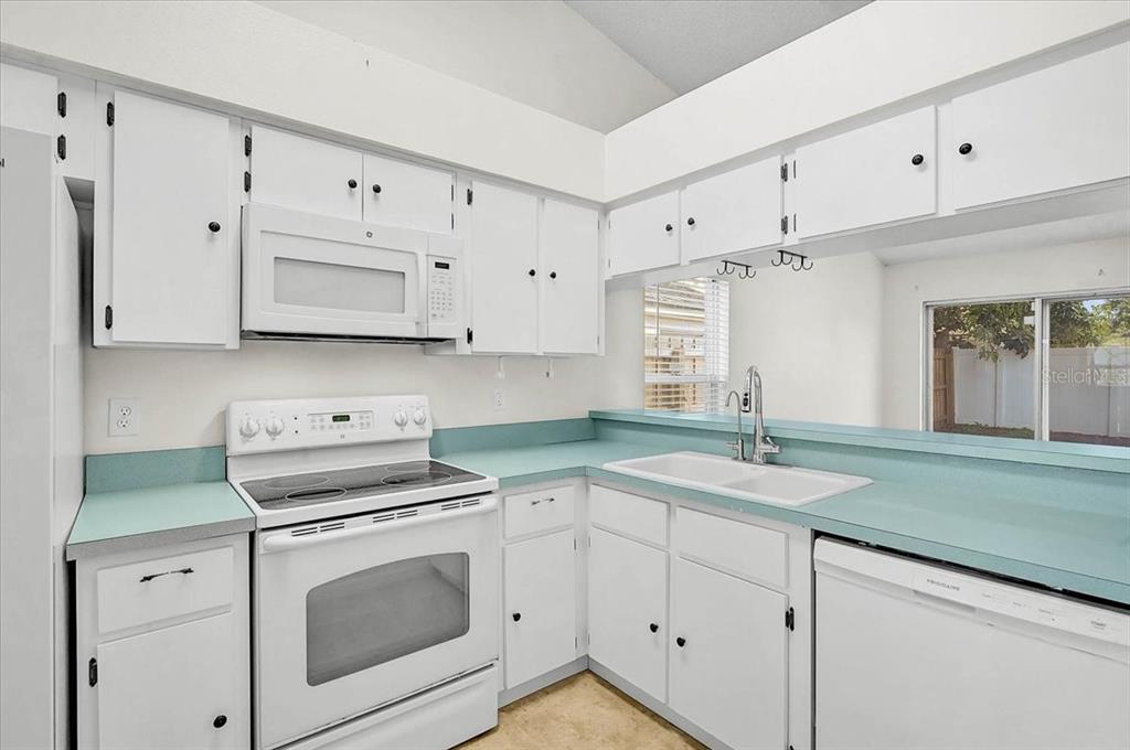 A kitchen features white cabinets, a white stove, a white dishwasher, and teal countertops — 13616 LARAWAY DRIVE, RIVERVIEW, FL