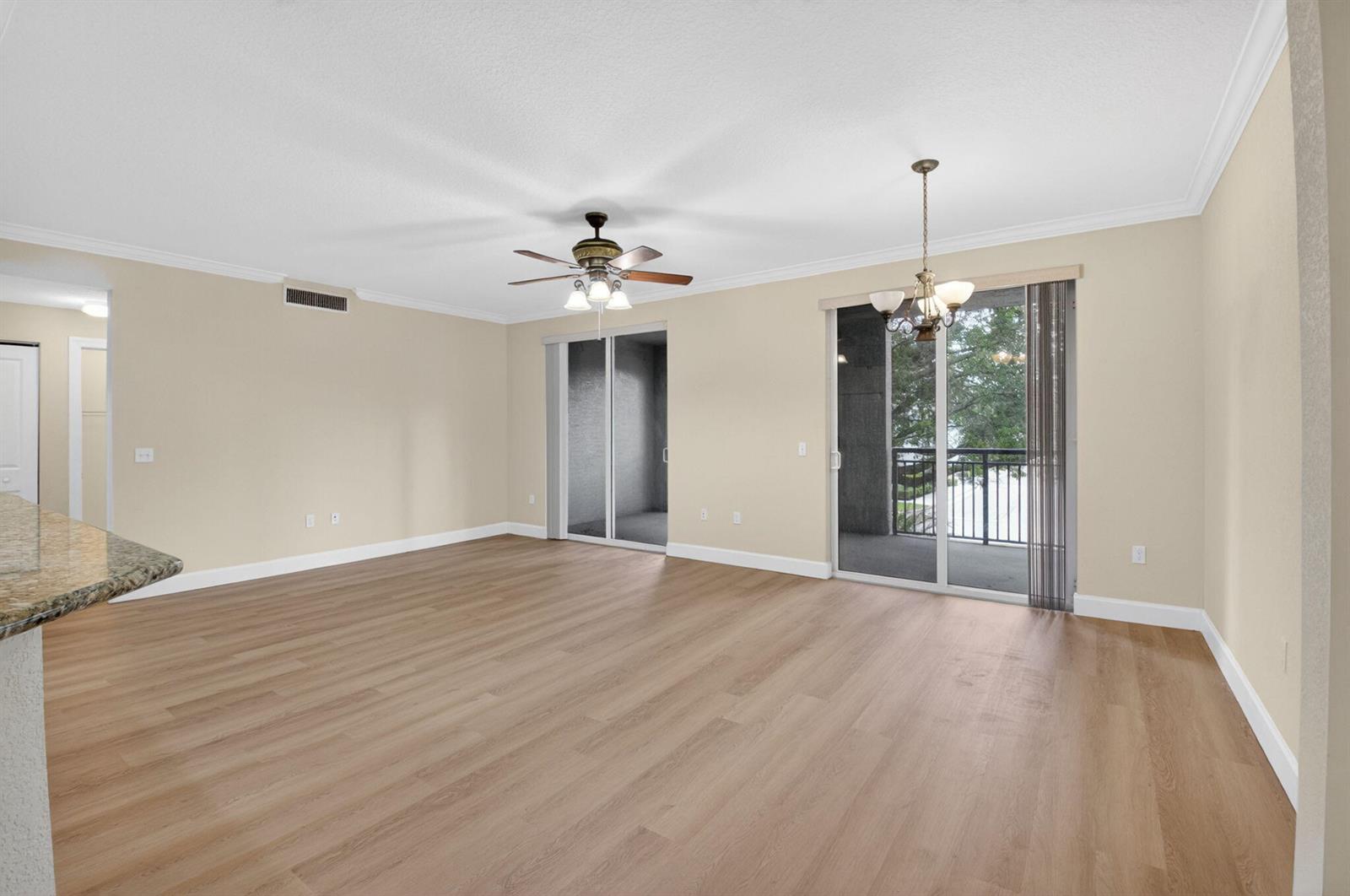 An empty living room with light wood flooring, a ceiling fan, and sliding glass doors — 1690 Renaissance Commons Boulevard # 1219, Boynton Beach FL 33426, BOYNTON BEACH, FL