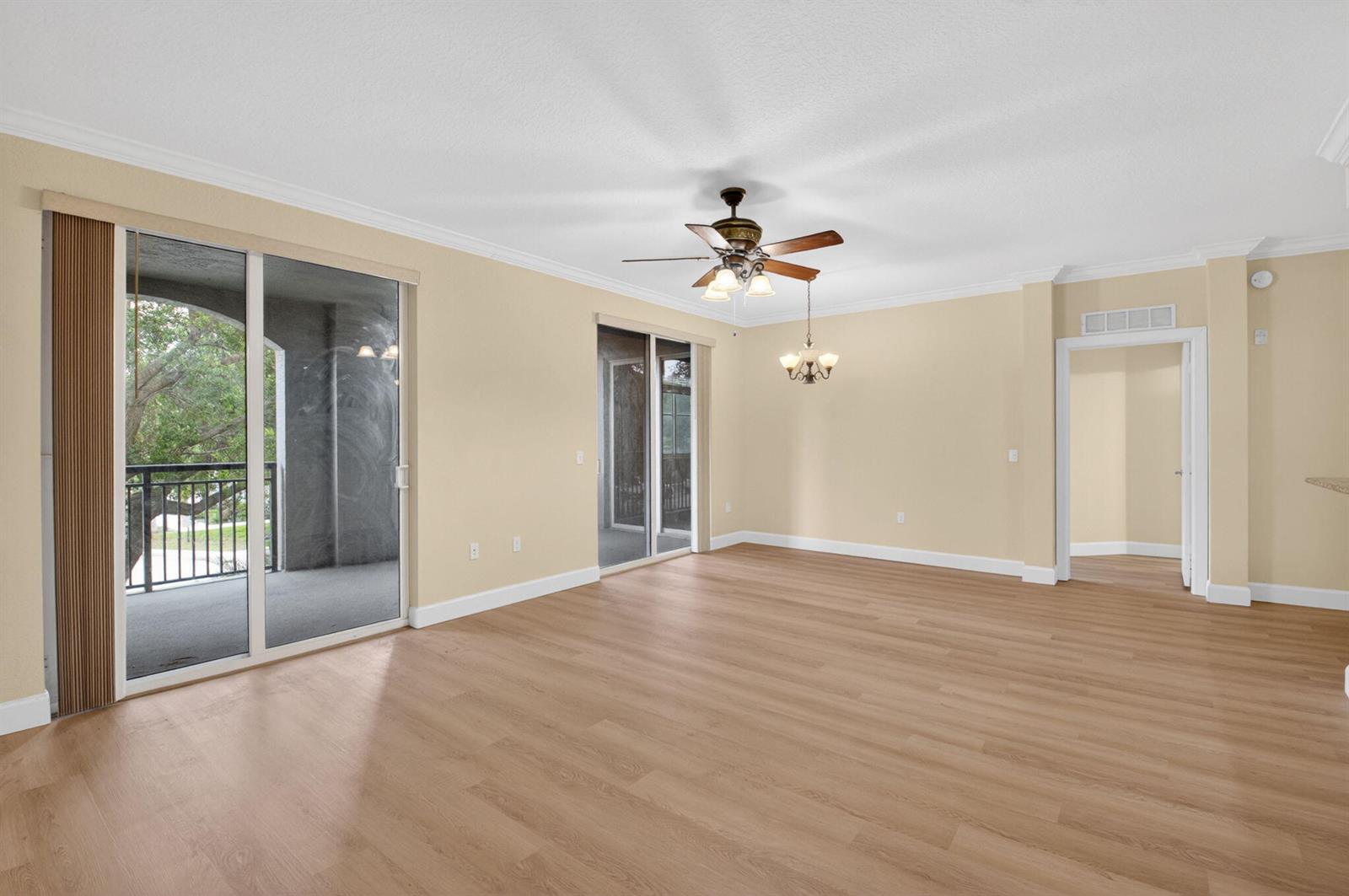 An empty living room with light wood flooring, a ceiling fan, and sliding glass doors — 1690 Renaissance Commons Boulevard # 1219, Boynton Beach FL 33426, BOYNTON BEACH, FL