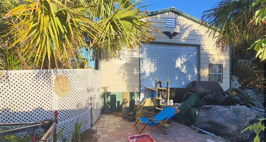 A metal storage shed with a roll-up door sits behind a white lattice fence — 18671 KERRVILLE CIRCLE, PORT CHARLOTTE, FL