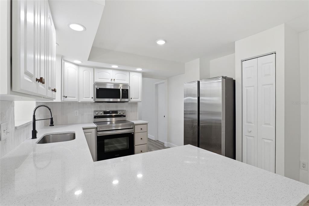 A modern kitchen features white cabinets, quartz countertops, stainless steel appliances, and a breakfast bar — 524 WESTMINSTER AVENUE, MELBOURNE, FL