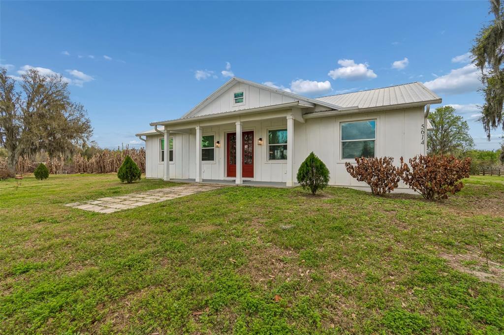 A white, single-story house with a metal roof and red double doors sits on grass — 5614 PLESS ROAD, PLANT CITY, FL