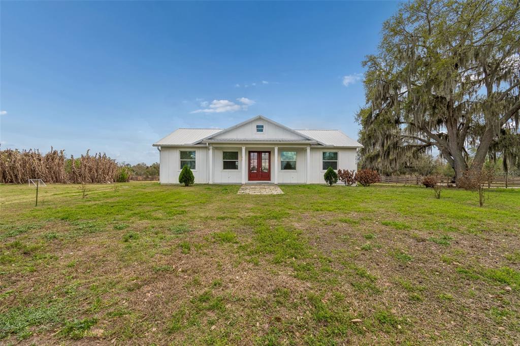 A white, single-story house with a metal roof and red front doors sits on grass — 5614 PLESS ROAD, PLANT CITY, FL