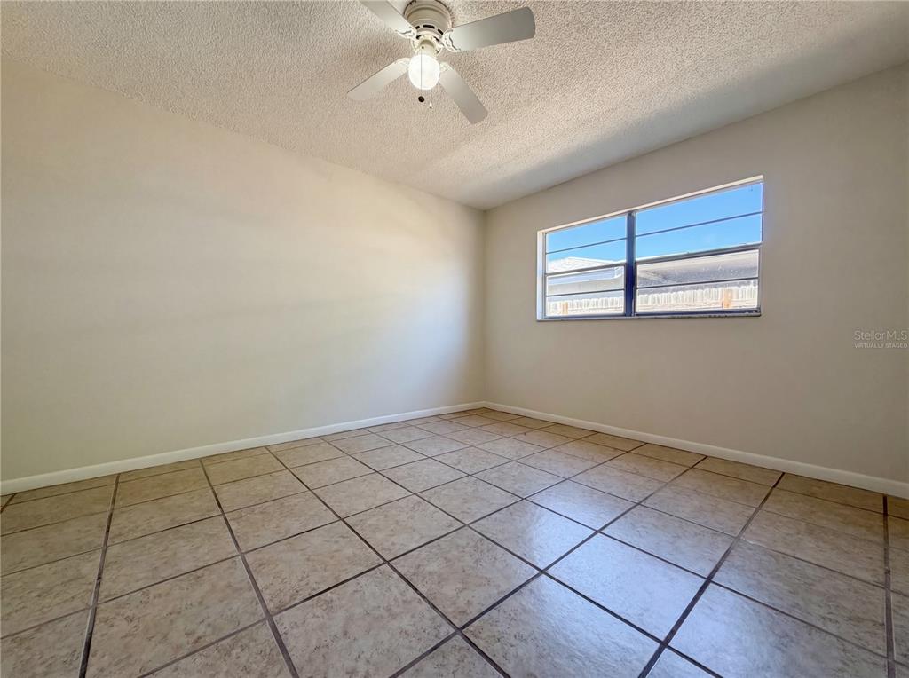 An empty bedroom features beige tile flooring, light-colored walls, and a ceiling fan — 909 WINCHESTER COURT, BRANDON, FL