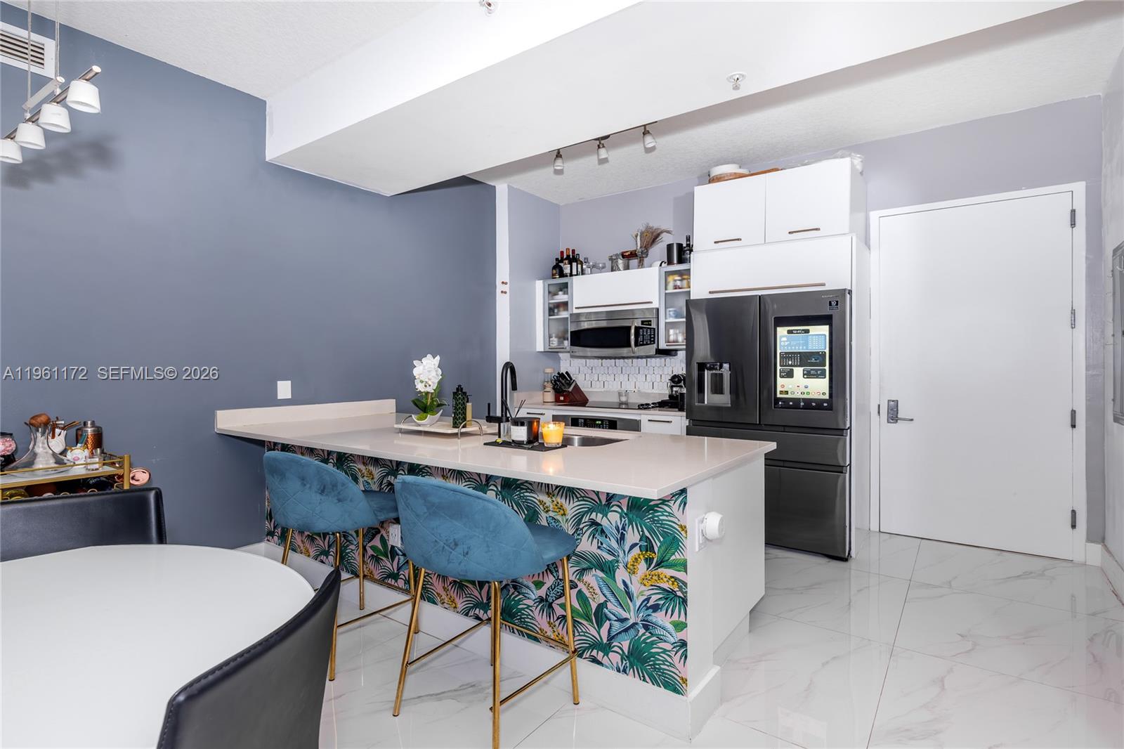 A kitchen features a tropical-patterned island, blue velvet barstools, and a smart refrigerator — 333 NE 24th St # 1912, Miami FL 33137, MIAMI, FL