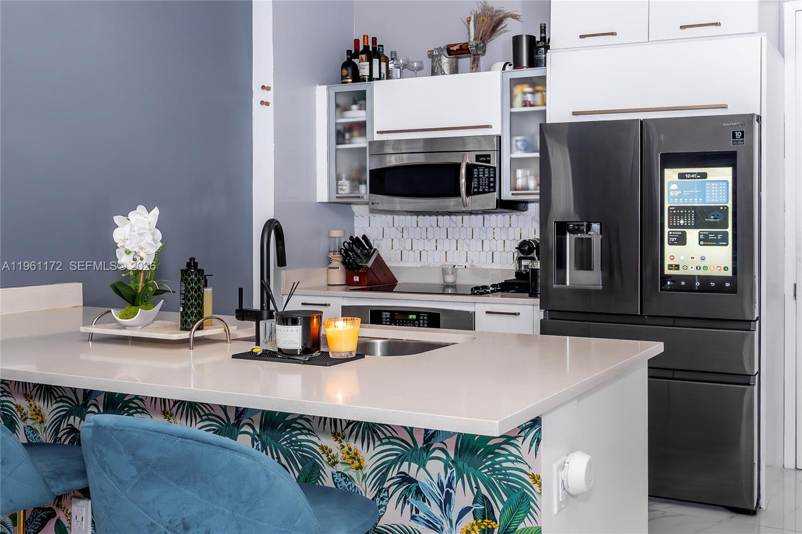 A modern kitchen features a quartz island, tropical wallpaper, and a smart refrigerator — 333 NE 24th St # 1912, Miami FL 33137, MIAMI, FL