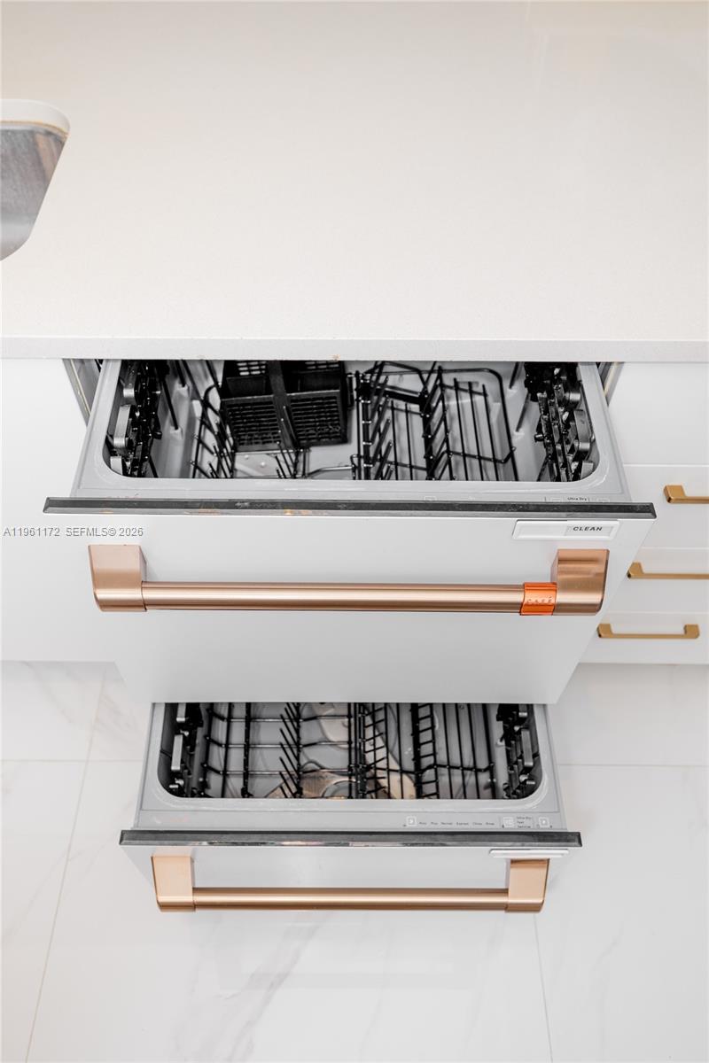 A white kitchen features a double-drawer dishwasher with copper-toned handles and white countertops — 333 NE 24th St # 1912, Miami FL 33137, MIAMI, FL