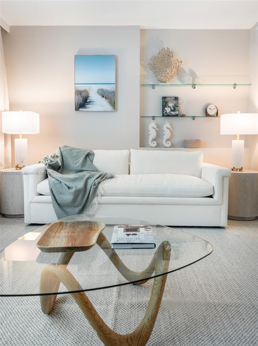 A bright living room features a white sofa, glass coffee table, and built-in shelving — 2301 Collins Ave # 836, Miami Beach FL 33139, MIAMI BEACH, FL