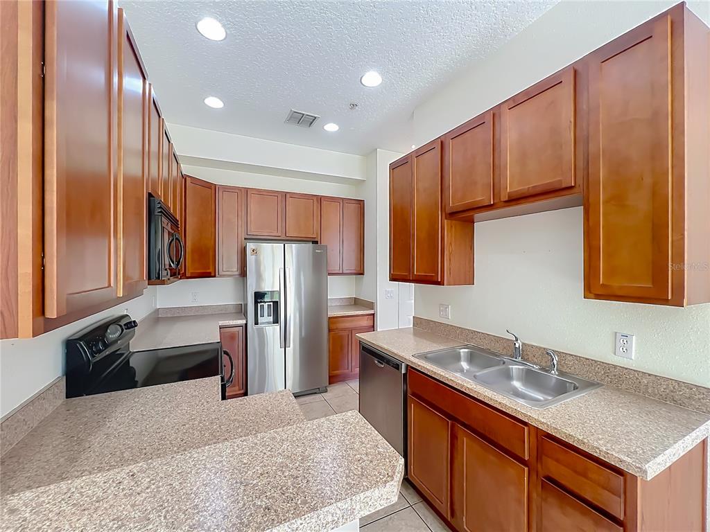 A kitchen features wood cabinets, stainless steel appliances, and speckled laminate countertops — 600 NORTHERN WAY UNIT 1804, WINTER SPRINGS, FL