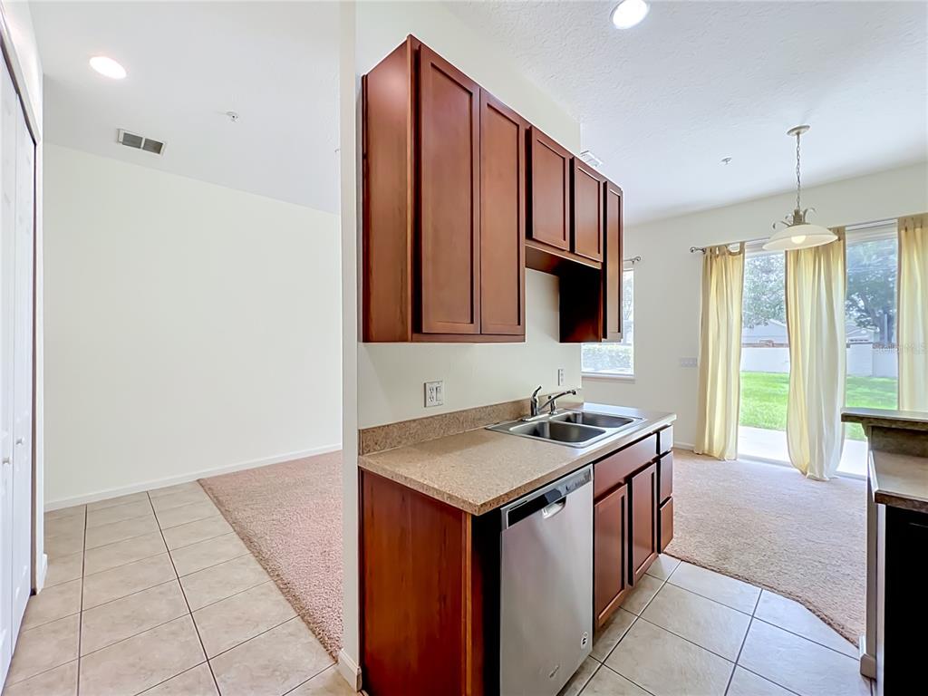 A kitchen features wood cabinets, a stainless steel dishwasher, and a sink with tile flooring — 600 NORTHERN WAY UNIT 1804, WINTER SPRINGS, FL