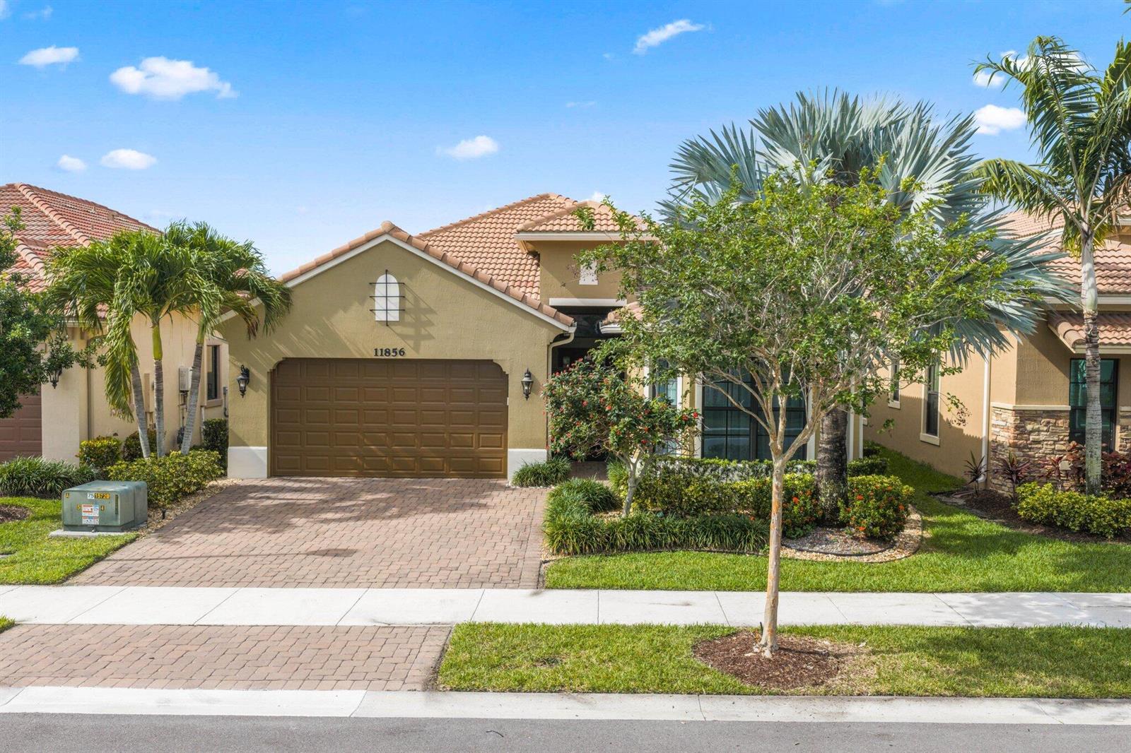 A single-story house with a brown garage door, tiled roof, and landscaped front yard — 11856 Leon Circle N, Parkland FL 33076, PARKLAND, FL